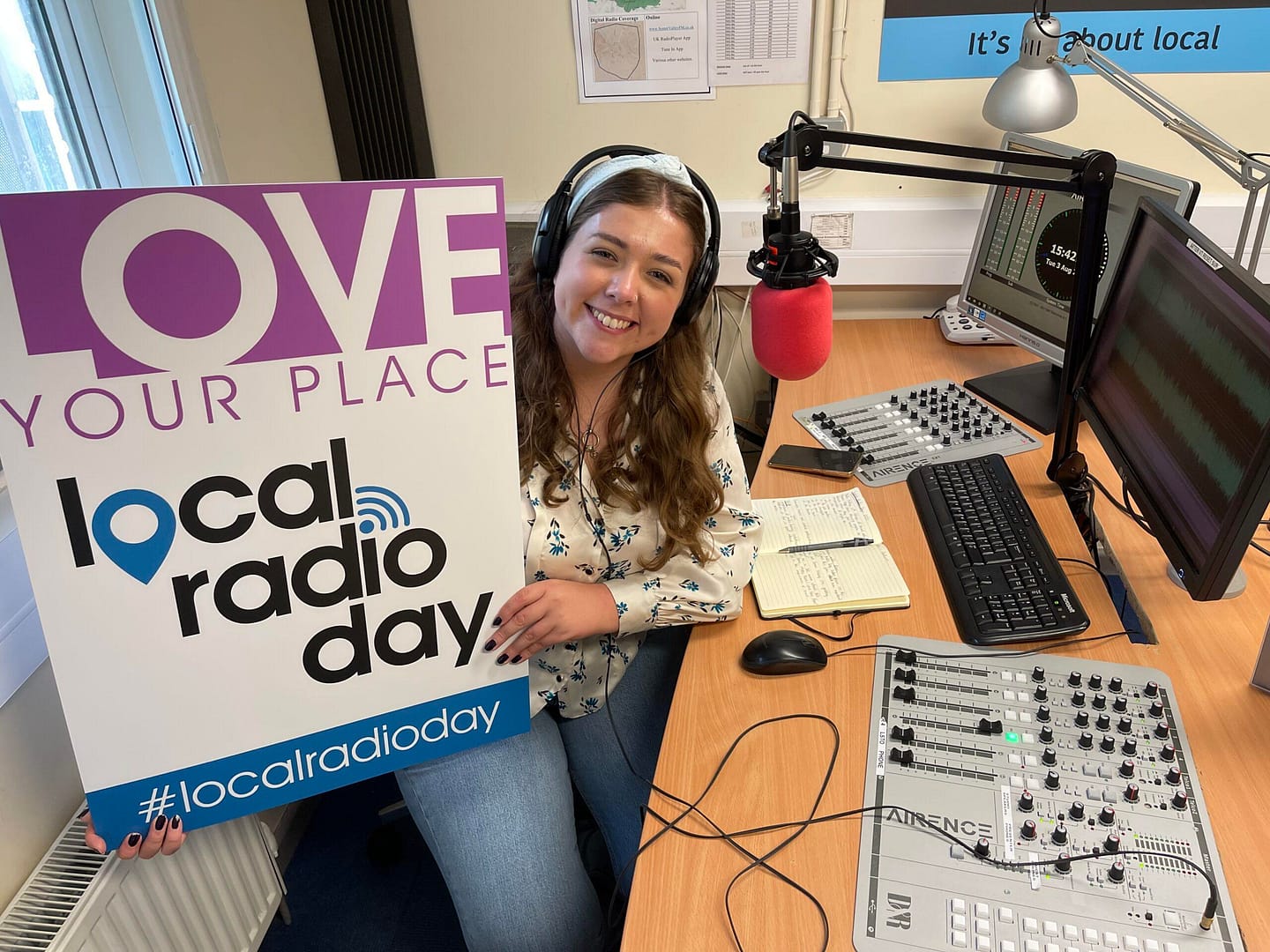 Gwen poses with Local Radio Day sign in community radio station Somer Valley FM's studio